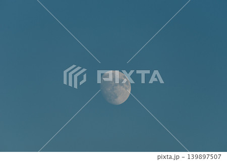 A nearly full moon set against a deep blue sky. 139897507