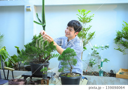 A man making bonsai pruning with precision care and craftsmanship A man making bonsai pruning with precision care and craftsmanship 139898064