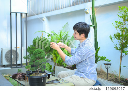 A man making bonsai pruning with precision care and craftsmanship A man making bonsai pruning with precision care and craftsmanship 139898067