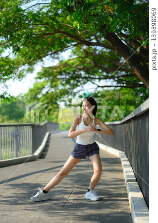 Runner woman stretching warmup on skywalk in park with urban city Runner woman stretching warmup on skywalk in park with urban city 139898069