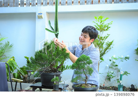 A man making bonsai pruning with precision care and craftsmanship A man making bonsai pruning with precision care and craftsmanship 139898076