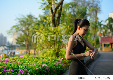 Young woman tracking health data in smartwatch at the park Young woman tracking health data in smartwatch at the park 139898080