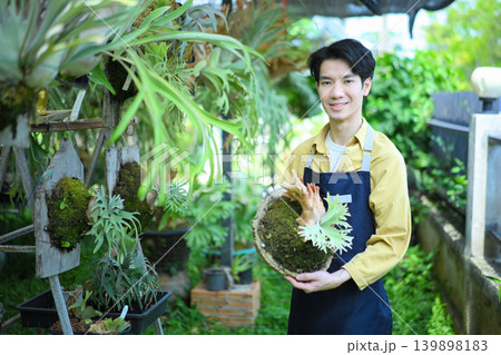 Male gardener holding staghorn fern, showcasing plant care, pride, and botanical expertise Male gardener holding staghorn fern, showcasing plant care, pride, and botanical expertise 139898183