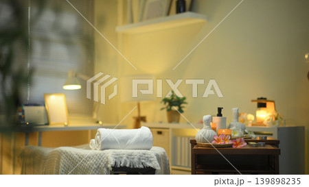 Realistic photo of a spa room with fresh flowers placed on a soft towel, Burning candles and aromatic reed freshener 139898235