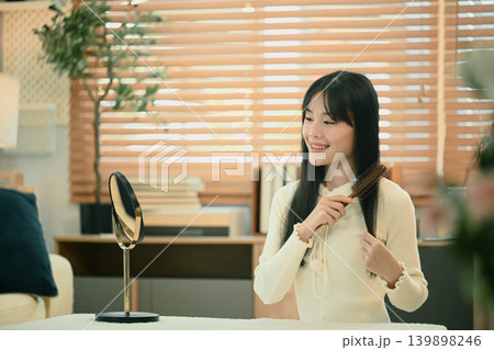 Asian woman combing good hair in living room 139898246