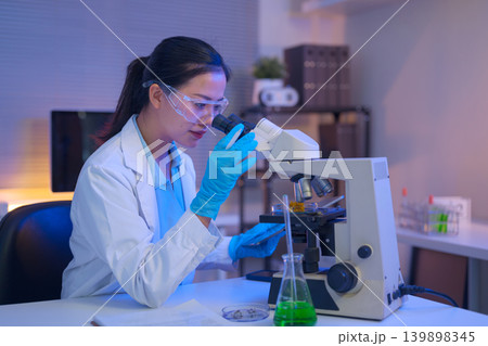 Female scientist using a microscope to analyze samples Female scientist using a microscope to analyze samples 139898345