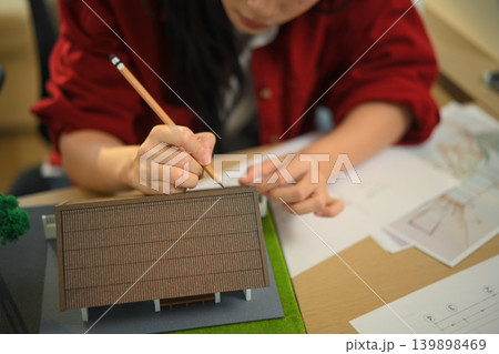 Closeup Female architect examining house model at office desk 139898469