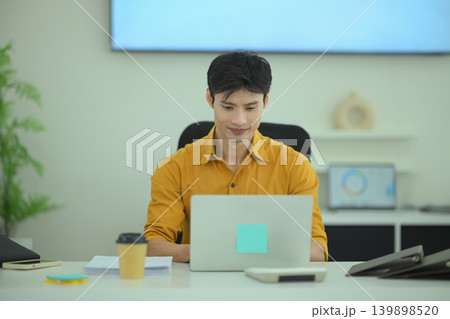 Businessman focused on laptop in office workspace Businessman focused on laptop in office workspace 139898520