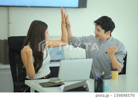 Colleagues high five after achieving business goal in the meeting room 139898570
