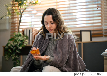 Woman taking medicine at living room Woman taking medicine at living room 139898636