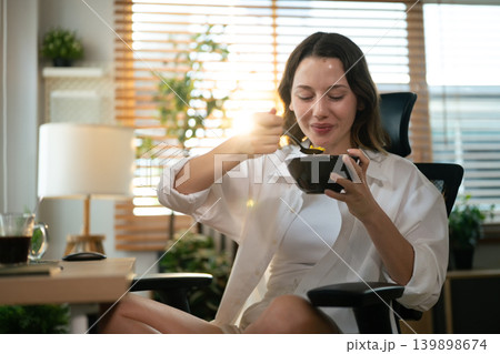 Remote worker eating breakfast while sitting at computer workspace. Remote worker eating breakfast while sitting at computer workspace. 139898674