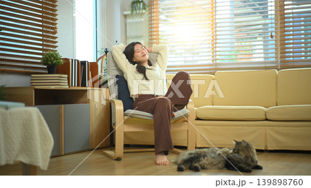 Woman stretching or relaxing in living room with cat on floor 139898760