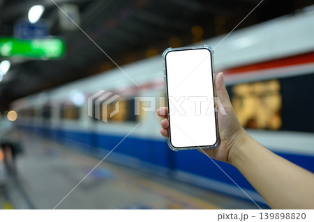 Hand holding smartphone at empty with clipping path in train station platform Hand holding smartphone at empty with clipping path in train station platform 139898820