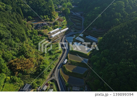 岡山県高梁市の棚田と山間の曲がりくねった道路を俯瞰した空撮写真 岡山県高梁市の棚田と山間の曲がりくねった道路を俯瞰した空撮写真 139899394