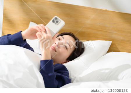 ベッドでスマホを操作する日本人女性 ベッドでスマホを操作する日本人女性 139900128