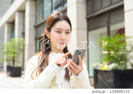 スマートフォンを操作する日本人ビジネスウーマン スマートフォンを操作する日本人ビジネスウーマン 139900135