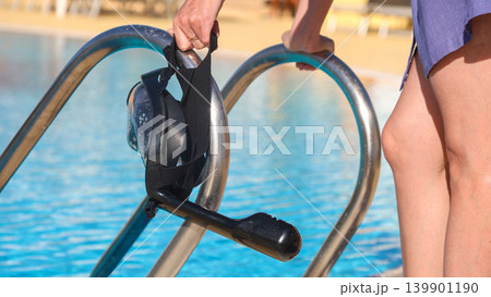 A diving mask in a woman's hand against the background of water A diving mask in a woman's hand against the background of water 139901190
