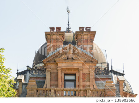 Crowning the rooftop of Greenwich's Altazimuth Pavilion, an ornate red-brick and terracotta facade exemplifies late Victorian craftsmanship. The central pediment features a detailed relief bust of Crowning the rooftop of Greenwich's Altazimuth Pavilion, an ornate red-brick and terracotta facade exemplifies late Victorian craftsmanship. The central pediment features a detailed relief bust of 139902666