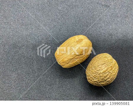 whole nutmeg seeds (Myristica fragrans), a popular aromatic spice. These seeds are grayish-brown ovals characterized by deeply furrowed, wrinkled surfaces. Known for its warm, slightly sweet, and pung whole nutmeg seeds (Myristica fragrans), a popular aromatic spice. These seeds are grayish-brown ovals characterized by deeply furrowed, wrinkled surfaces. Known for its warm, slightly sweet, and pung 139905081