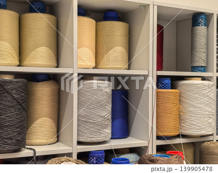 Large industrial yarn cones on shelves in carpet manufacturing factory Large industrial yarn cones on shelves in carpet manufacturing factory 139905478