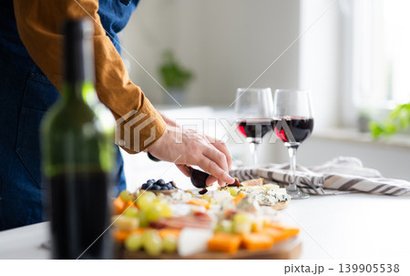 Man In Apron Preparing Cheese Board And Wine Glasses 139905538
