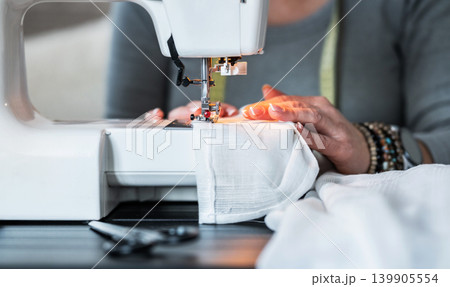 Sewing a Garment on a White Machine in a Workspace 139905554
