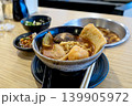 Delicious Japanese ramen bowl with noodles, shiitake mushroom, pork belly, and fish cake on a wooden table. Asian fusion cuisine served with side dishes and chopsticks in a modern restaurant. 139905972
