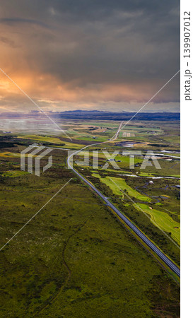 Aerial View of Icelandic Road Amid Green Fields and Volcanic Terrain Aerial View of Icelandic Road Amid Green Fields and Volcanic Terrain 139907012