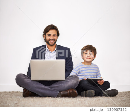 Father, happy kid and portrait with laptop, tablet and learning with boy at home by wall. Smile, child and dad on computer with tech for remote work, love or connection of family together on floor 139907332