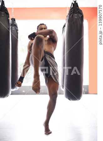 Man, kick boxing and bag with training, knee and combat for exercise with balance, power and precision in gym. African athlete, person or fighter with workout, fitness or strike for challenge in dojo Man, kick boxing and bag with training, knee and combat for exercise with balance, power and precision in gym. African athlete, person or fighter with workout, fitness or strike for challenge in dojo 139907570