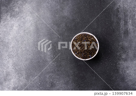 Granules of dried organic Chinese green tea with herbal additives. Dry green tea Granules of dried organic Chinese green tea with herbal additives. Dry green tea 139907634