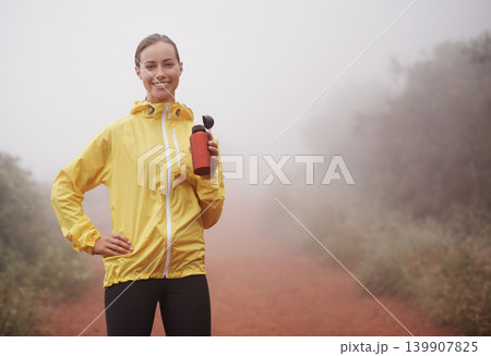 Nature, fitness and portrait of woman drinking water for running on dirt road with marathon training. Sports, workout and athlete enjoying beverage for hydration on misty outdoor cardio exercise. Nature, fitness and portrait of woman drinking water for running on dirt road with marathon training. Sports, workout and athlete enjoying beverage for hydration on misty outdoor cardio exercise. 139907825