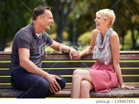 Love, laughing and happy couple on a park bench with funny conversation, gossip or bonding outdoors together. Trust, communication or people sharing comic, chat or speaking on travel, trip or holiday 139907881