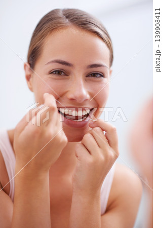 Portrait, mouth and dental floss for oral hygiene care with woman in bathroom of home for teeth whitening. Face, product and face of young person in apartment to prevent tooth decay or gum disease Portrait, mouth and dental floss for oral hygiene care with woman in bathroom of home for teeth whitening. Face, product and face of young person in apartment to prevent tooth decay or gum disease 139908411
