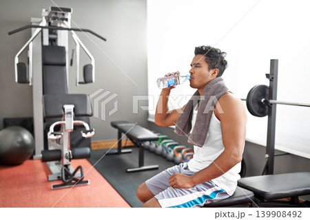 Fitness, gym and man drinking water for training, wellness or exercise recovery, break or resting. Workout, hydration and thirsty male athlete with sports drink after intense, cardio or bodybuilding 139908492