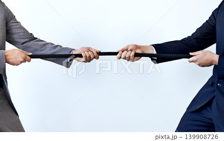 Business people, rope and tug of war for challenge, mission or strength of rivals on a blue studio background. Closeup of employees or colleagues hands pulling strong cable for competition on mockup Business people, rope and tug of war for challenge, mission or strength of rivals on a blue studio background. Closeup of employees or colleagues hands pulling strong cable for competition on mockup 139908726