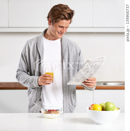 Breakfast, juice and man with newspaper in kitchen for information at modern apartment. Nutrition, cereal and young male person drinking healthy beverage and reading public journalism at home. 139908737