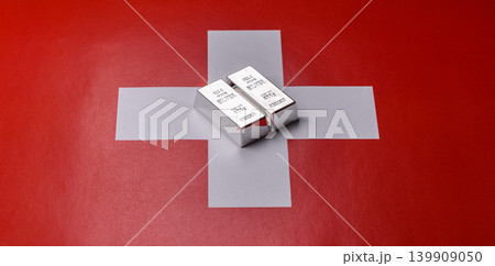 A silver bar, white metal against a backdrop of Swiss flag, as a concept for the sales. A silver bar 139909050