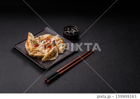 Gyoza, Chinese or Japanese meat dumplings, is an Asian food with hot peppers. Gyoza with meat Gyoza, Chinese or Japanese meat dumplings, is an Asian food with hot peppers. Gyoza with meat 139909163