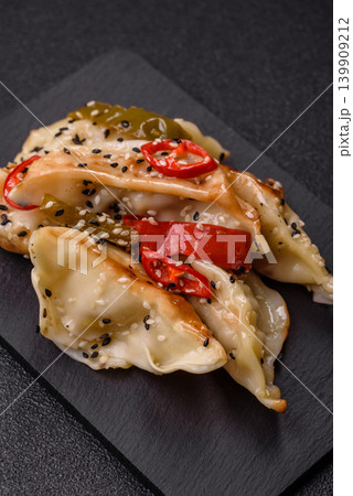 Gyoza, Chinese or Japanese meat dumplings, is an Asian food with hot peppers. Gyoza with meat Gyoza, Chinese or Japanese meat dumplings, is an Asian food with hot peppers. Gyoza with meat 139909212