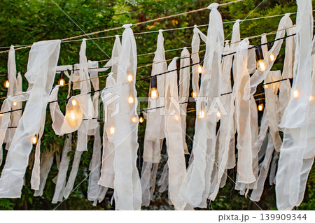 dim lamps and scraps of white cloth on ropes 139909344