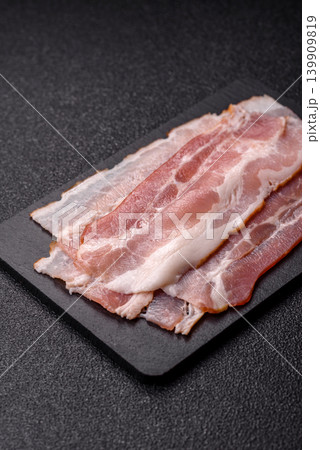 Raw fresh bacon slices with layers of meat or prosciutto with salt and spices. Raw bacon Raw fresh bacon slices with layers of meat or prosciutto with salt and spices. Raw bacon 139909819