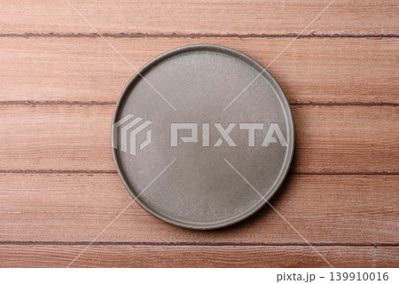 An empty ceramic round plate, kitchen utensils for a dinner table. An empty plate An empty ceramic round plate, kitchen utensils for a dinner table. An empty plate 139910016