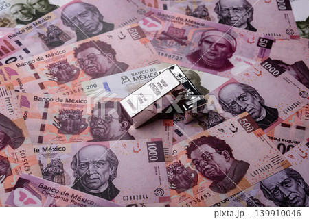 A silver bar, white metal against a backdrop of Mexican money, concept for the sales market 139910046