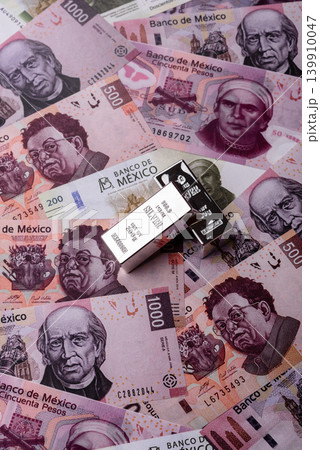 A silver bar, white metal against a backdrop of Mexican money, concept for the sales market A silver bar, white metal against a backdrop of Mexican money, concept for the sales market 139910047