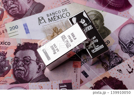 A silver bar, white metal against a backdrop of Mexican money, concept for the sales market A silver bar, white metal against a backdrop of Mexican money, concept for the sales market 139910050