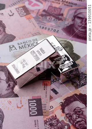 A silver bar, white metal against a backdrop of Mexican money, concept for the sales market 139910051