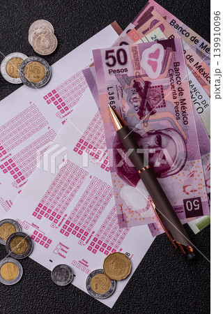 Lottery ticket, Mexican banknotes, and a pen, chance to win big, gambling. Lottery ticket Lottery ticket, Mexican banknotes, and a pen, chance to win big, gambling. Lottery ticket 139910096