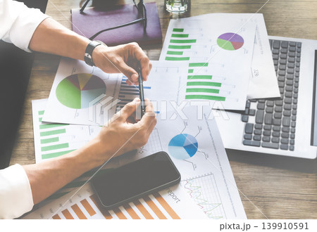 Businessperson reviews graphs with pen 139910591