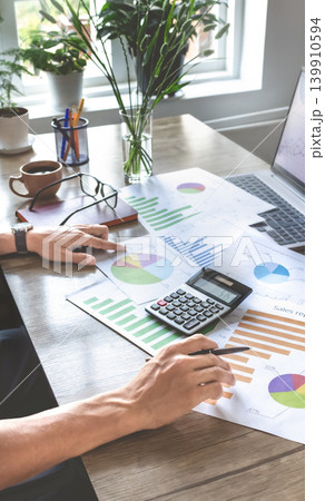 Businessperson reviews business graphs on desk Businessperson reviews business graphs on desk 139910594